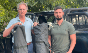 Protect Ukraine co-founder Jaap Scholten by a pickup truck, holding equipment bags delivered for the war effort.