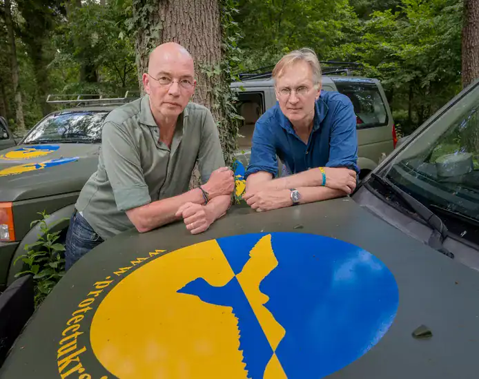 Authors and Protect Ukraine ambassadors Tommy Wieringa and Jaap Scholten leaning on a donated vehicle featuring the foundation's logo.