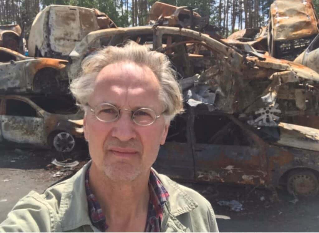 Jaap Scholten in front of a pile of cars damaged by Russian attacks on Bucha and Irpin.