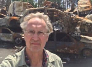 Jaap Scholten in front of a pile of cars damaged by Russian attacks on Bucha and Irpin.
