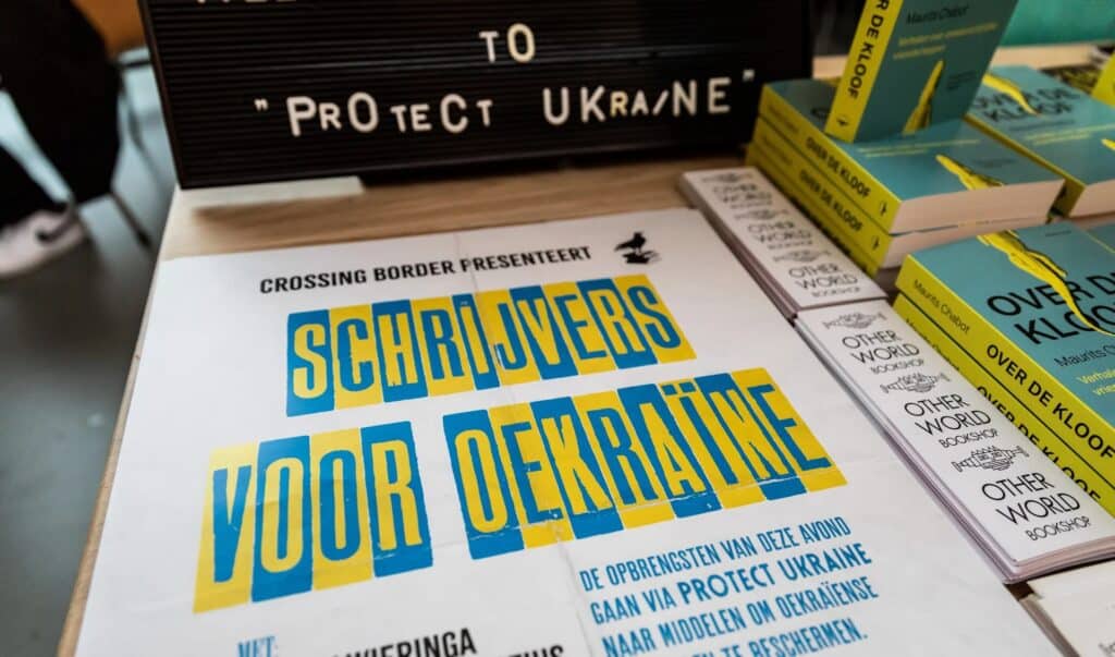 Flyer for a 'Schrijvers voor Oekraïne' (Writers for Ukraine) event, displayed in a bookshop.