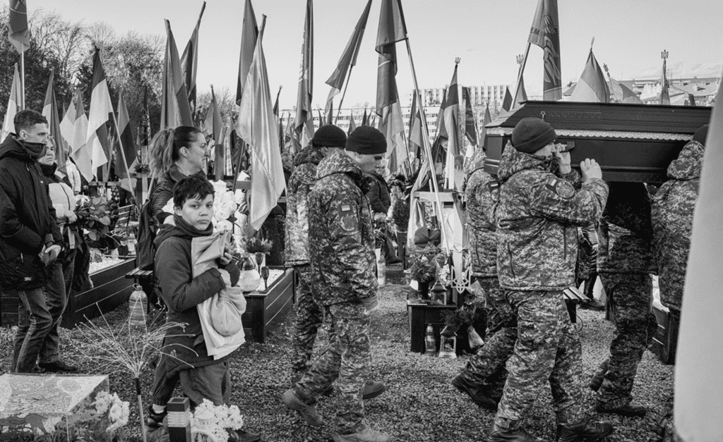 Funeral of a fallen soldier at a military cemetery in Ukraine, showing the human cost of the conflict.