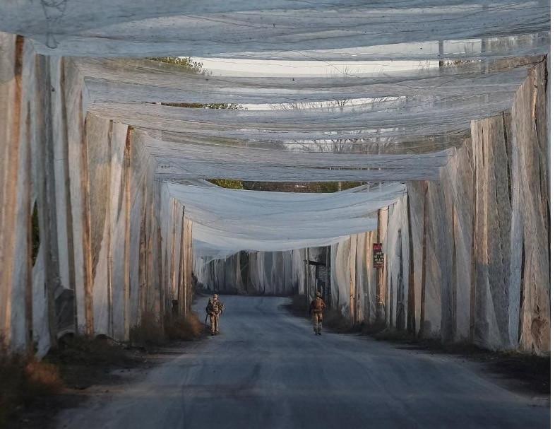 Anti-drone netting stretched across a road to protect against incoming drones.