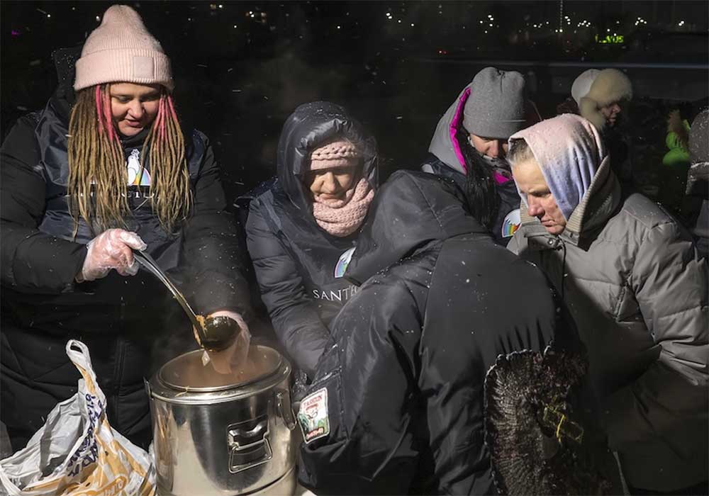 A volunteer distributing hot soup to elderly residents in freezing winter conditions.